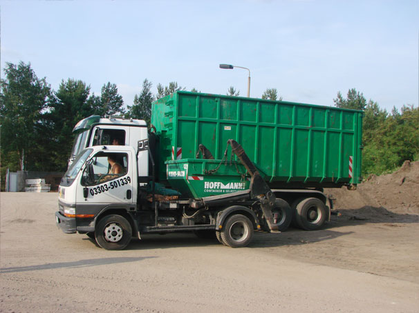 LKW stellt eine Absetzmulde neben einen Abrollcontainer auf dem Betriebshof